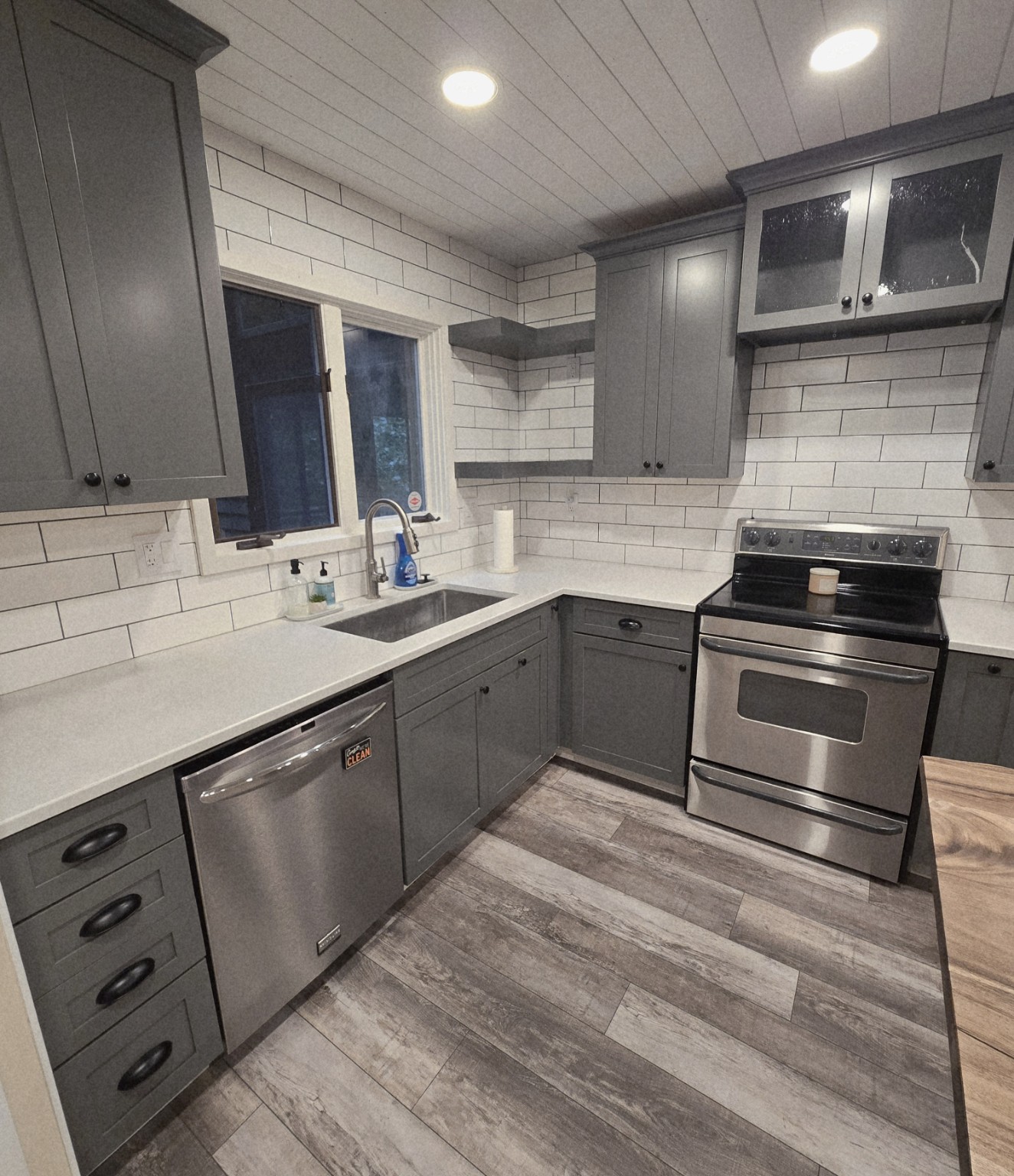 Kitchen cleaned by R&H, with gray cabinets, white counters and stainless steel appliances